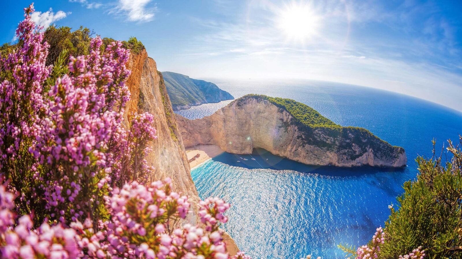 Pink spring blossoms framing Navagio (Shipwreck) Beach with turquoise water below