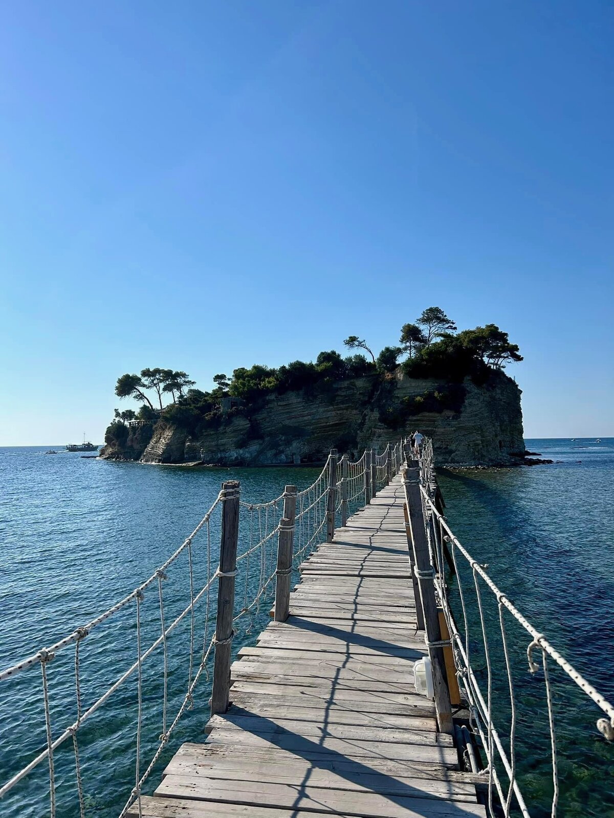 Walking onto the wooden suspension bridge towards Cameo Island under a clear blue sky