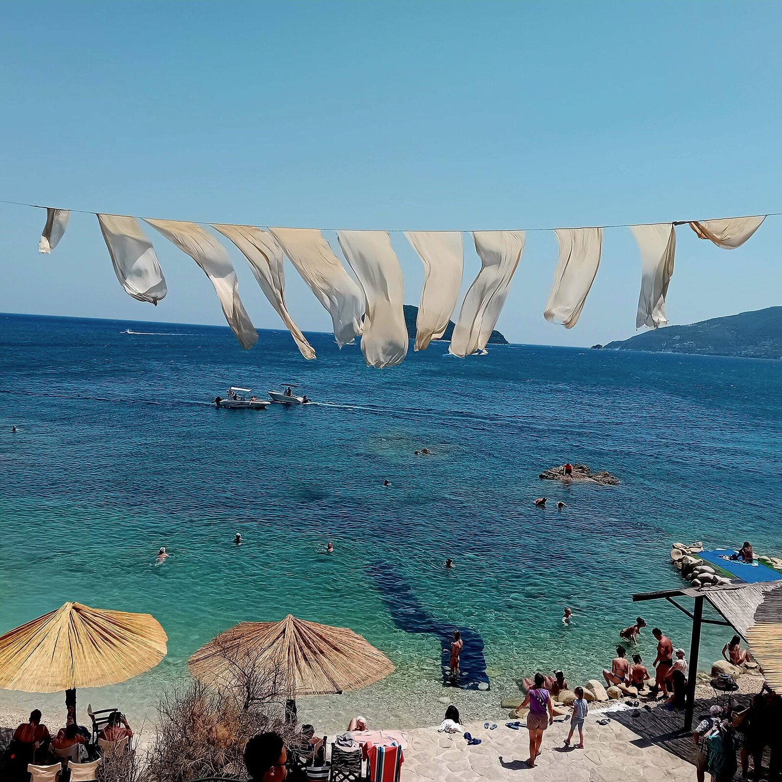 White fabric bunting fluttering above swimmers in the turquoise cove at Cameo Island