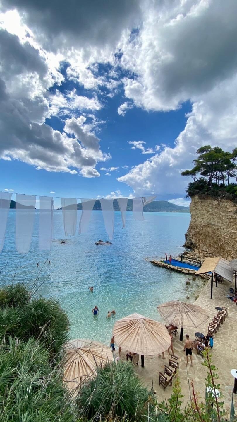 View from the cliff at Cameo Island with reed umbrellas, sun loungers and the turquoise cove below
