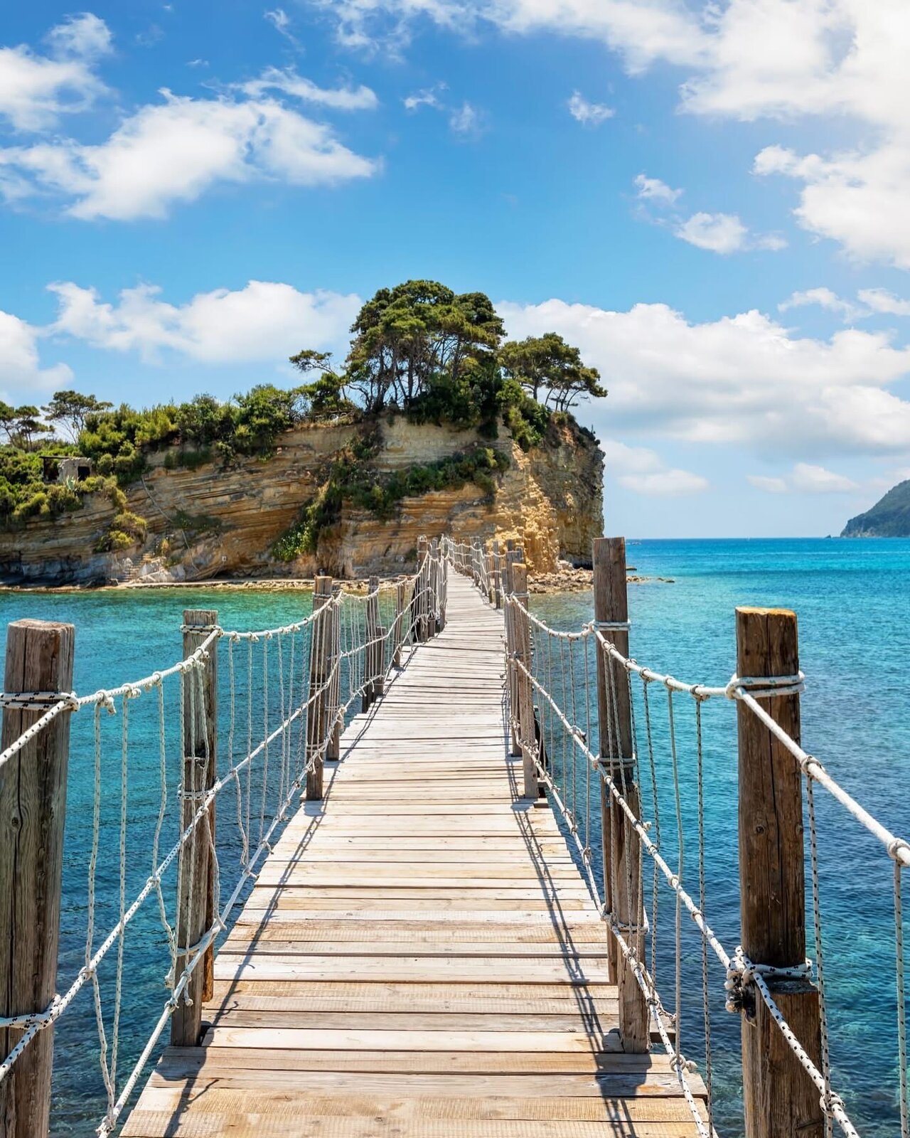 The rope-handrailed bridge stretching to Cameo Island under dramatic clouds