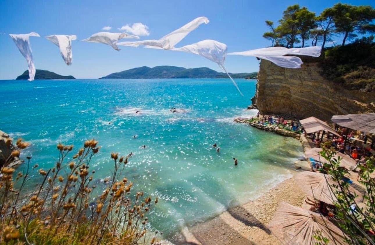 Wide view of the wooden bridge running across turquoise water to the pine-covered Cameo Island