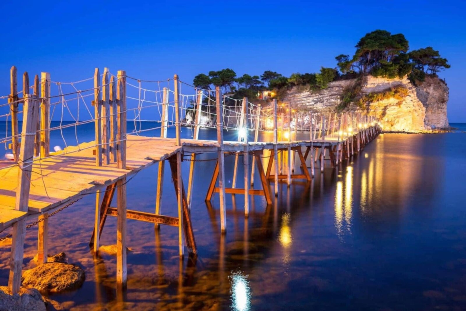 Long-exposure night view of the wooden bridge and Cameo Island lit up at blue hour