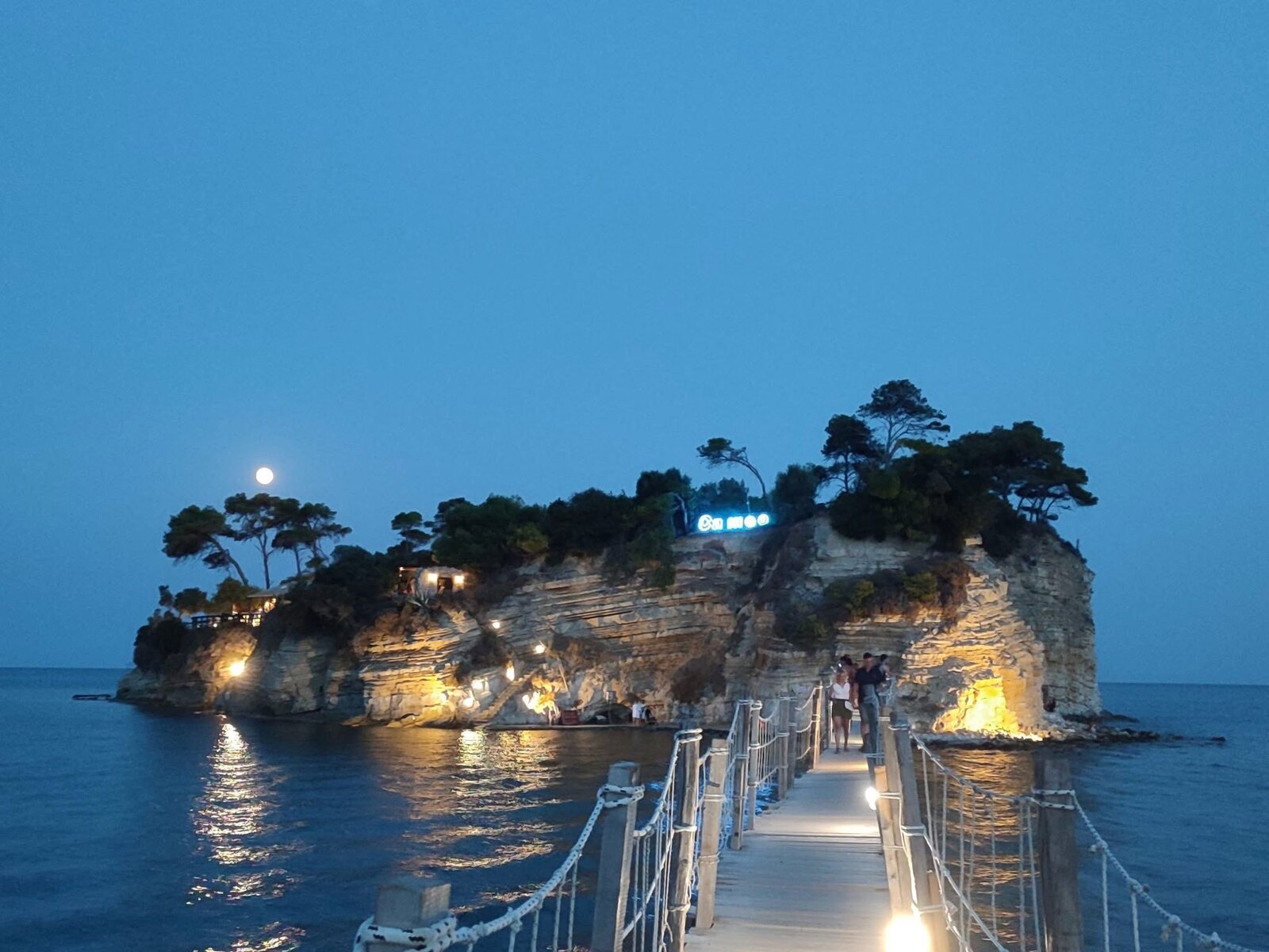 Evening view of Cameo Island with the illuminated "Cameo" sign and a full moon rising