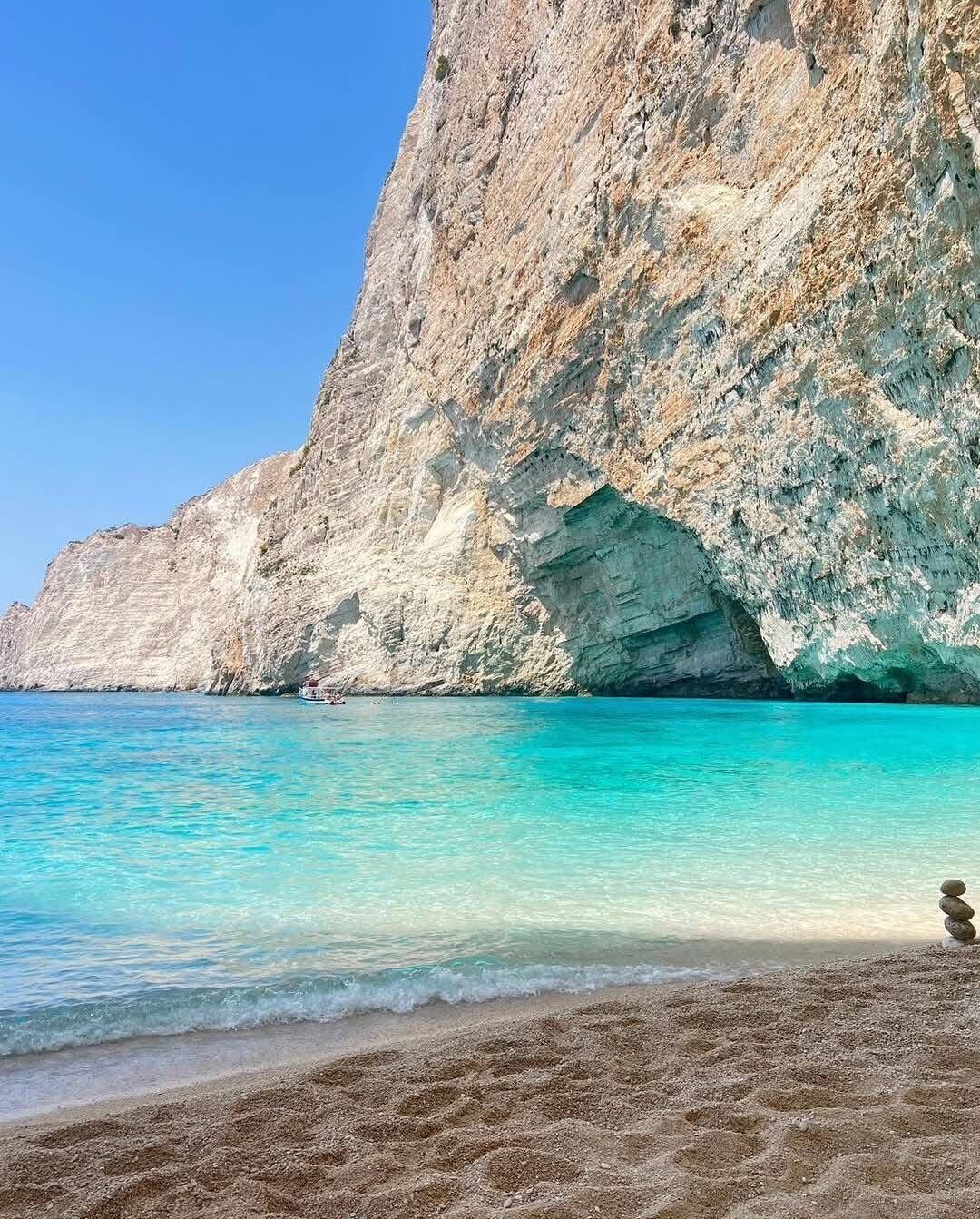 Towering white limestone cliff and turquoise water at Eros Cave beach