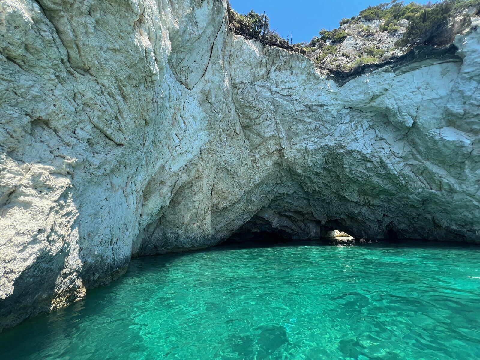 Wide white limestone cliff face with cave entrances along the southern Zakynthos coast