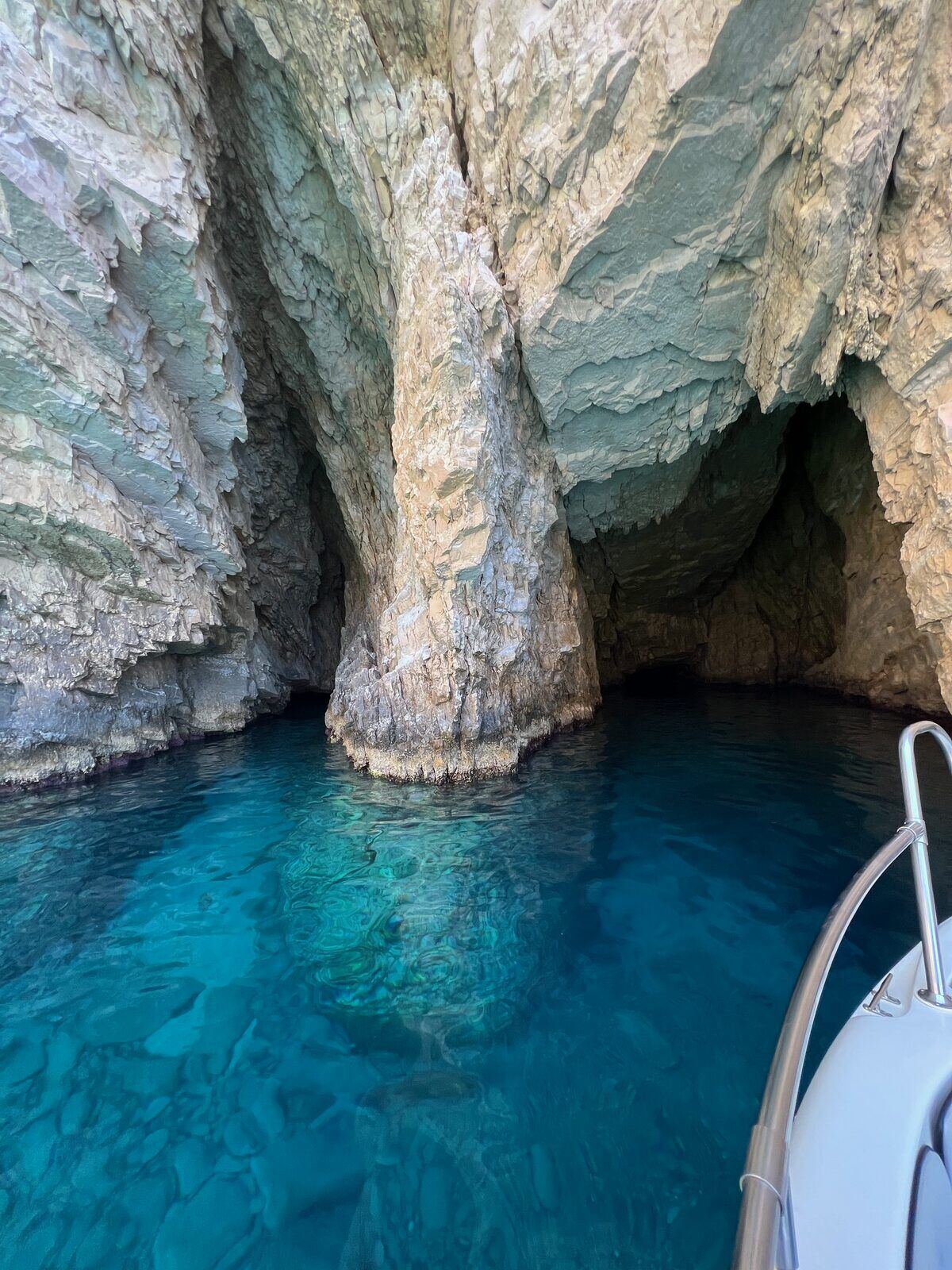 Inside a Keri sea cave with towering limestone pillars and crystal-clear turquoise water
