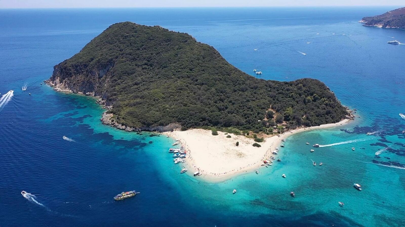 Wide aerial view of Marathonisi Island with boats anchored around the sandy beach