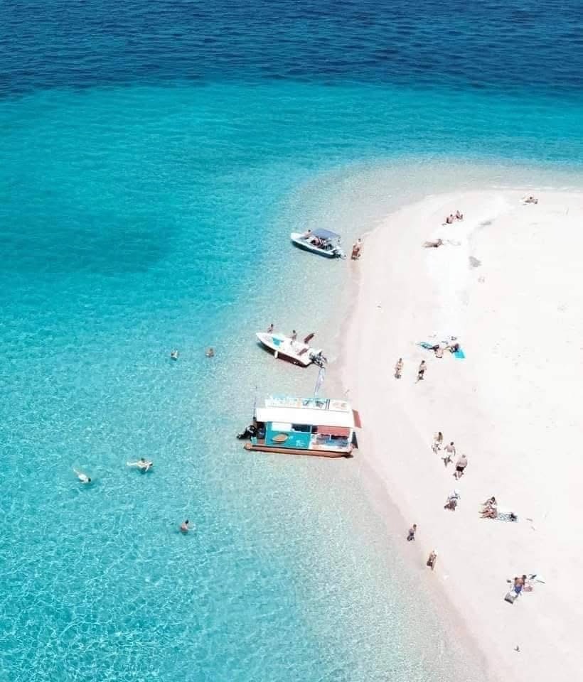Aerial close-up of visitors swimming and sunbathing on Marathonisi white sand beach