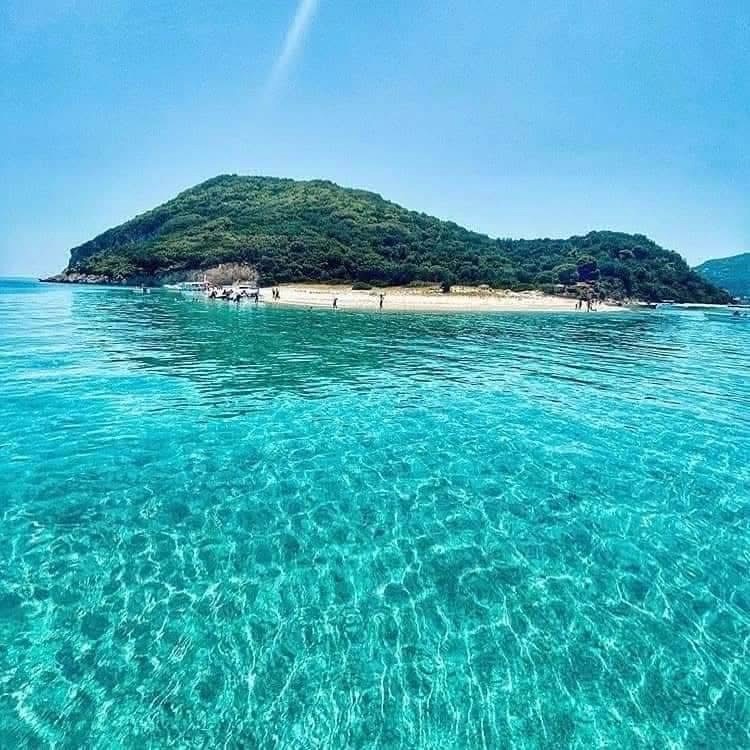 Marathonisi Island seen from the water with turquoise shallows and green hillside