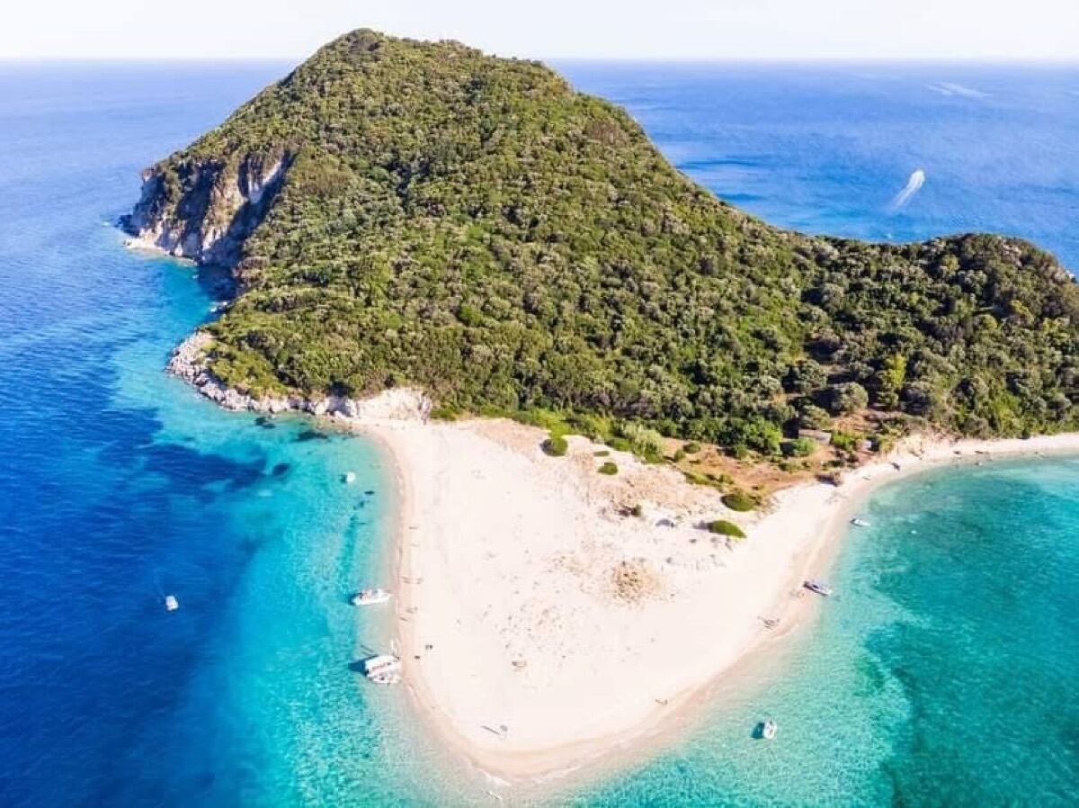 Aerial view of Marathonisi Turtle Island showing its turtle-like shape with white sand beach and turquoise water