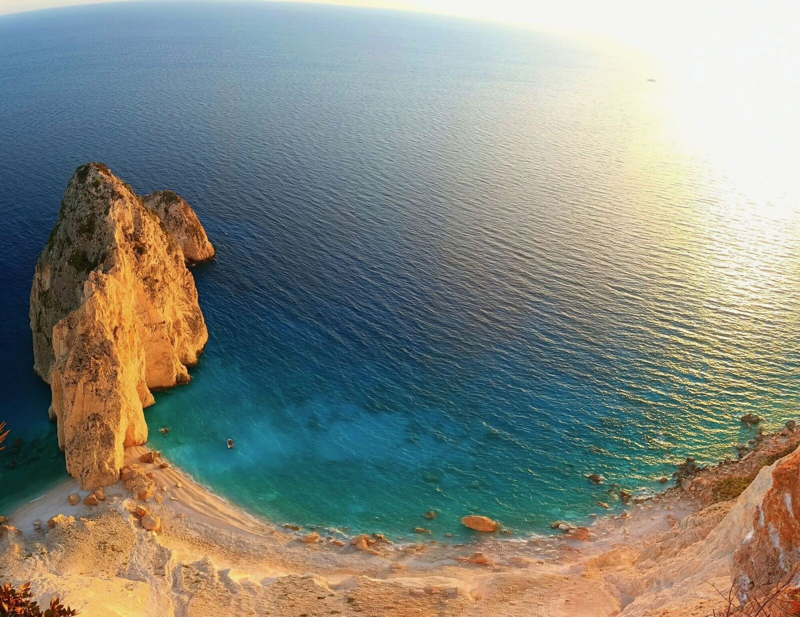 Wide-angle sunset view of Myzithres rock with turquoise cove below