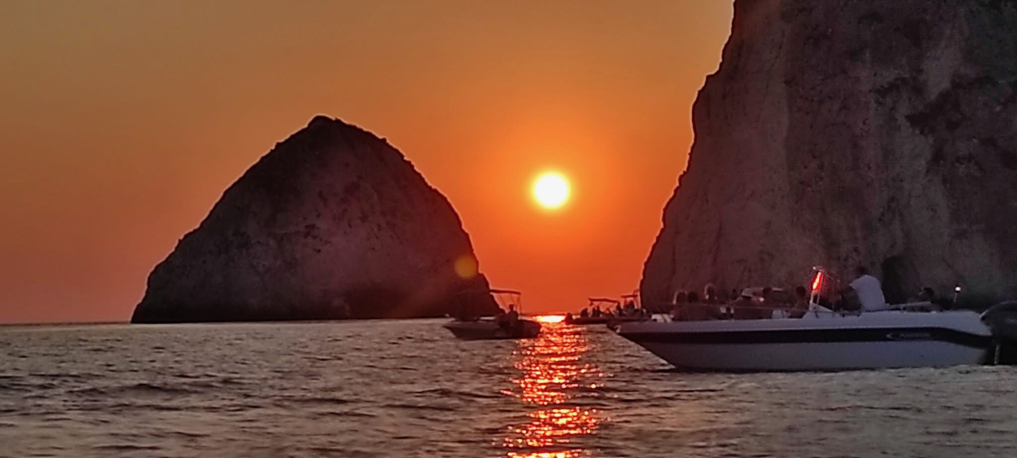 Sunset silhouette of Myzithres rocks with boats on the water