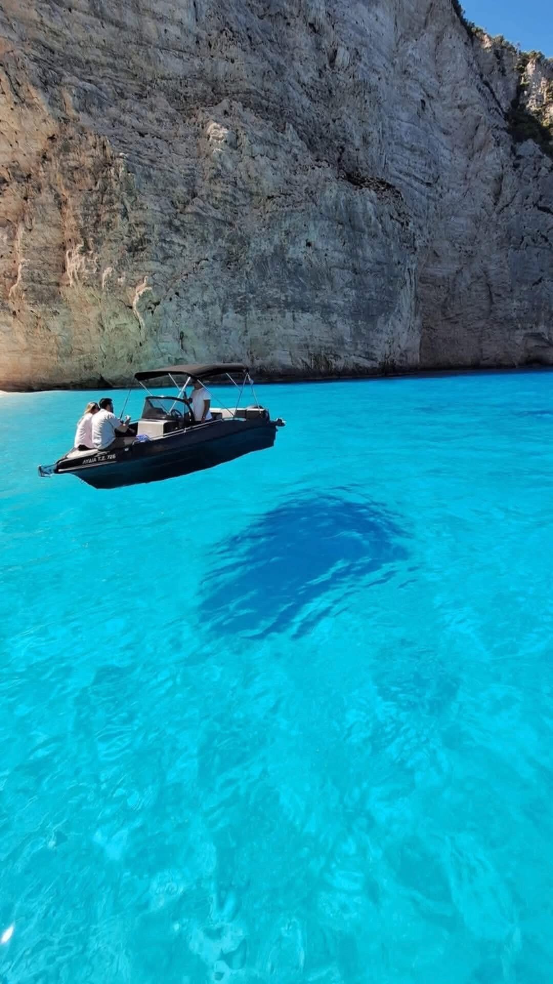 Boat floating on crystal clear turquoise water near Myzithres cliffs