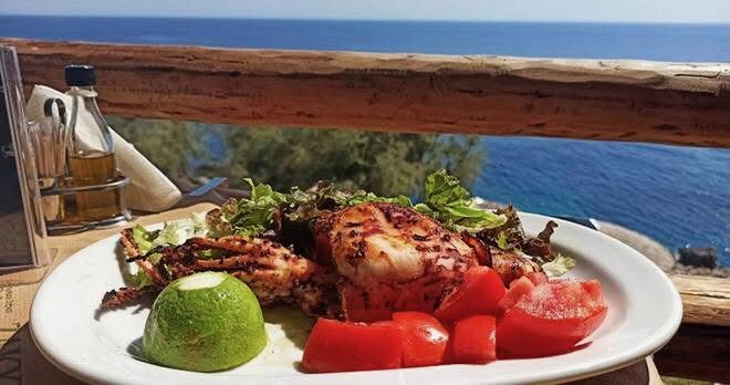 Plate of grilled seafood served on the Porto Limnionas taverna terrace with the sea behind