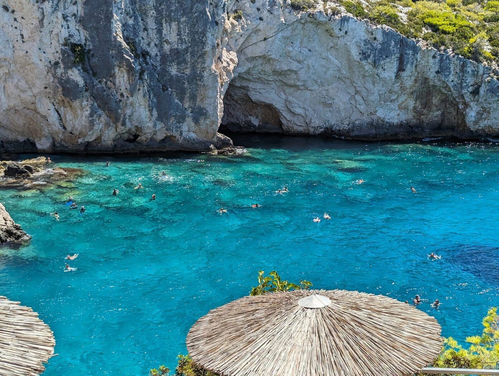 View from the taverna at Porto Limnionas under straw umbrellas across the turquoise cove