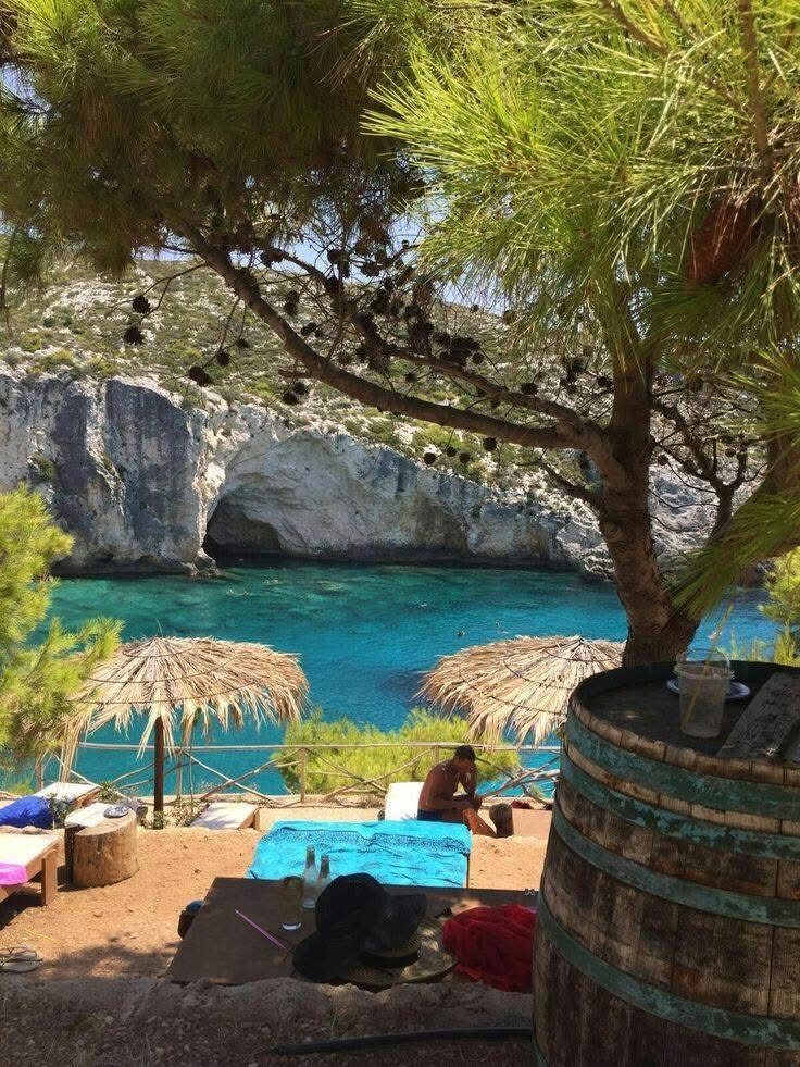 Sun loungers under thatched umbrellas on the rocky platform overlooking Porto Limnionas