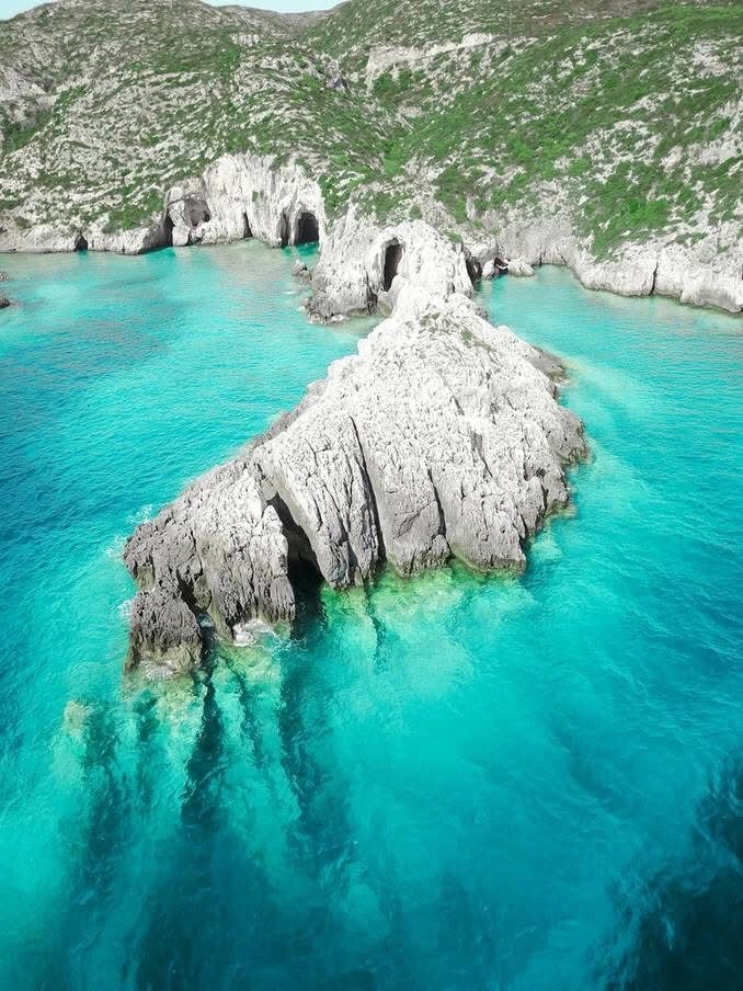 Pale limestone rock formation rising from the turquoise shallows at Porto Limnionas
