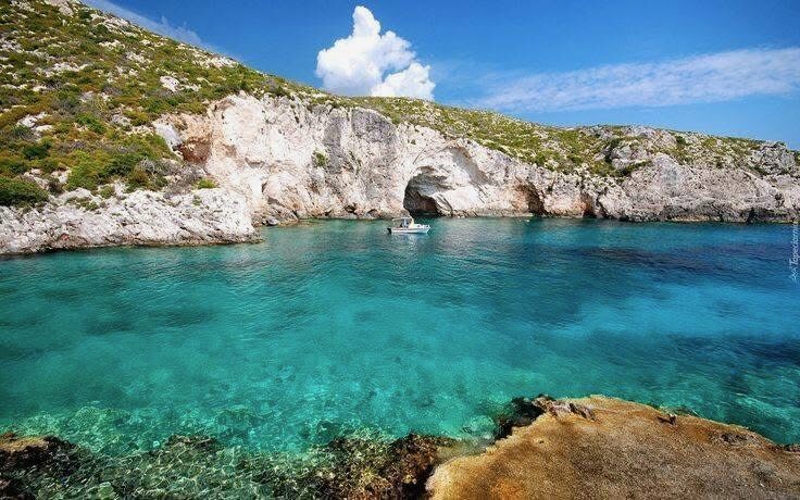 Sea arch and small cave carved into the cliff above the turquoise water at Porto Limnionas