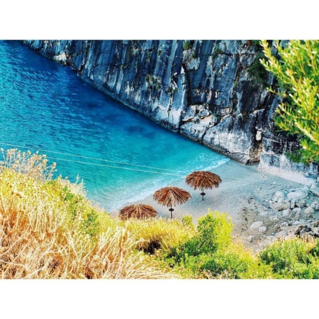 Vibrant overhead view of Xigia Beach with straw umbrellas and turquoise water