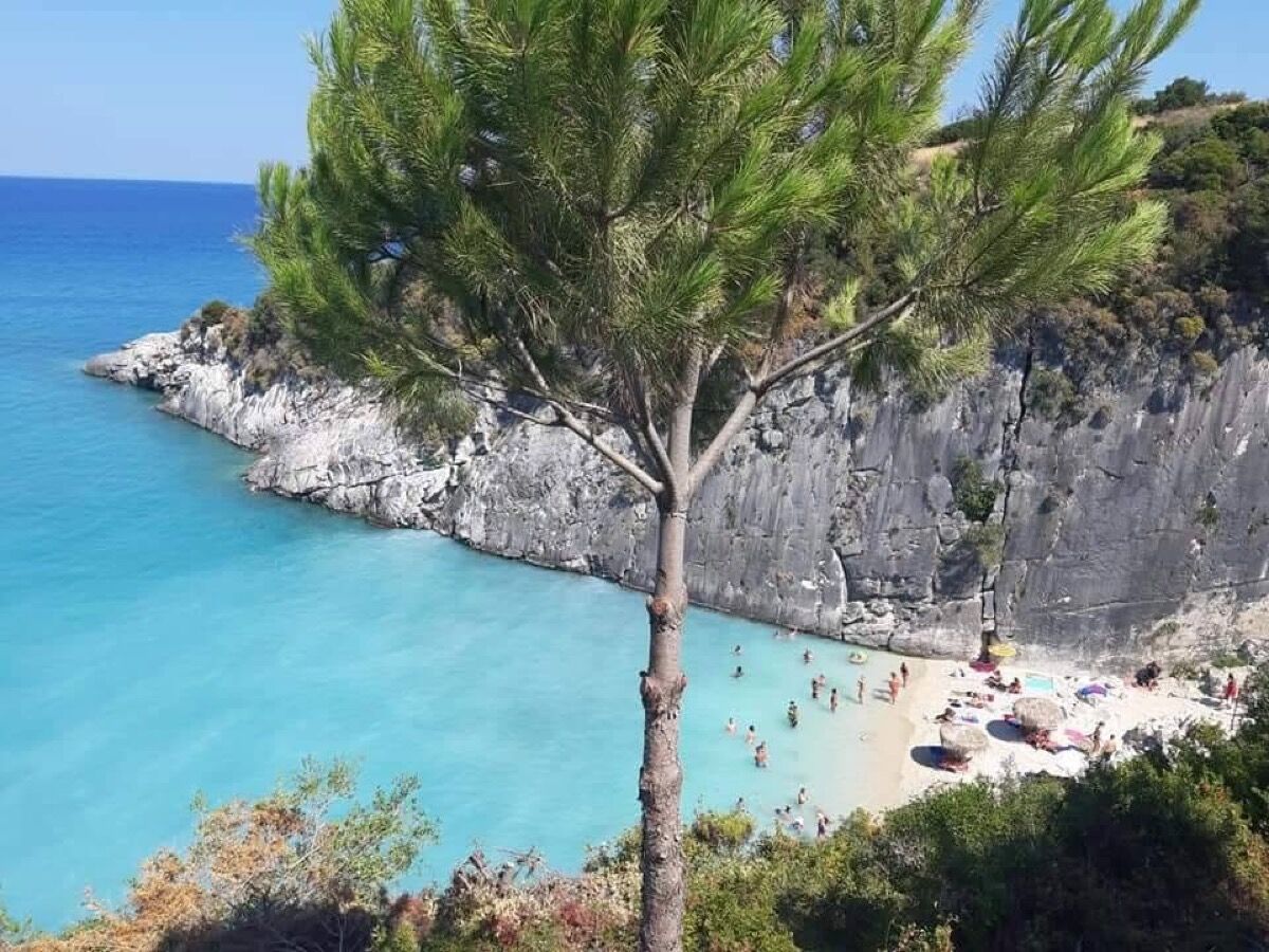 Aerial view of Xigia Sulphur Beach with turquoise water, pine tree, and limestone cliffs
