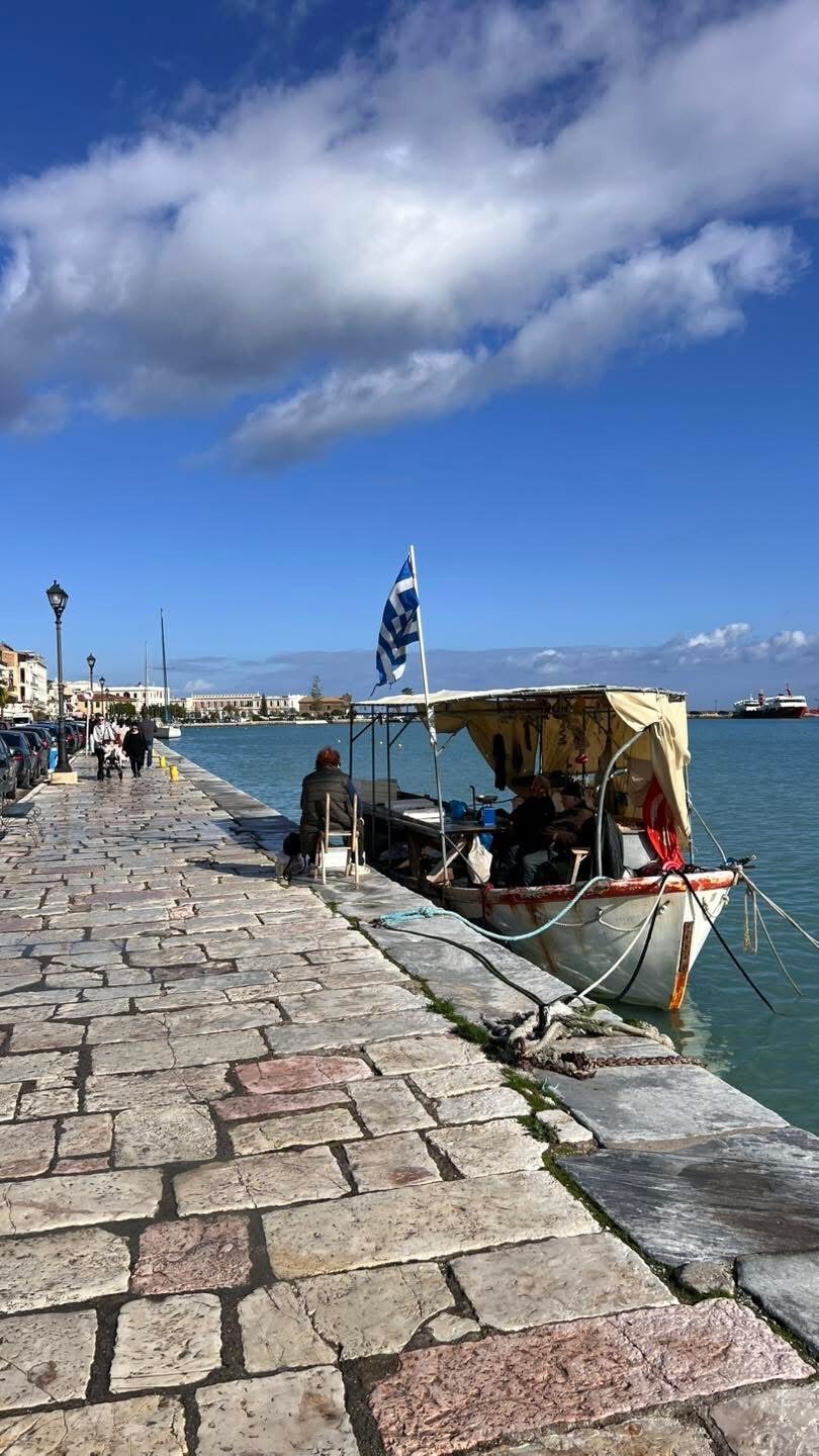 Fishing boat with Greek flag on the stone harbour promenade