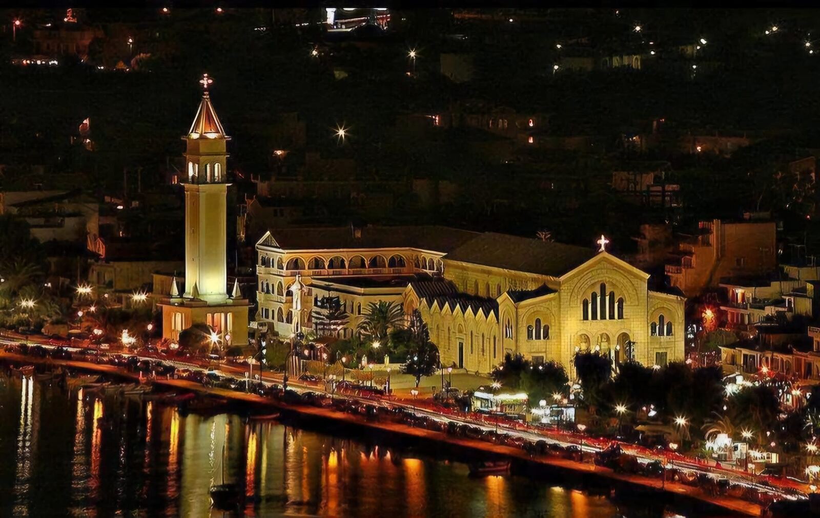 Agios Dionysios church illuminated at night with reflections on the water
