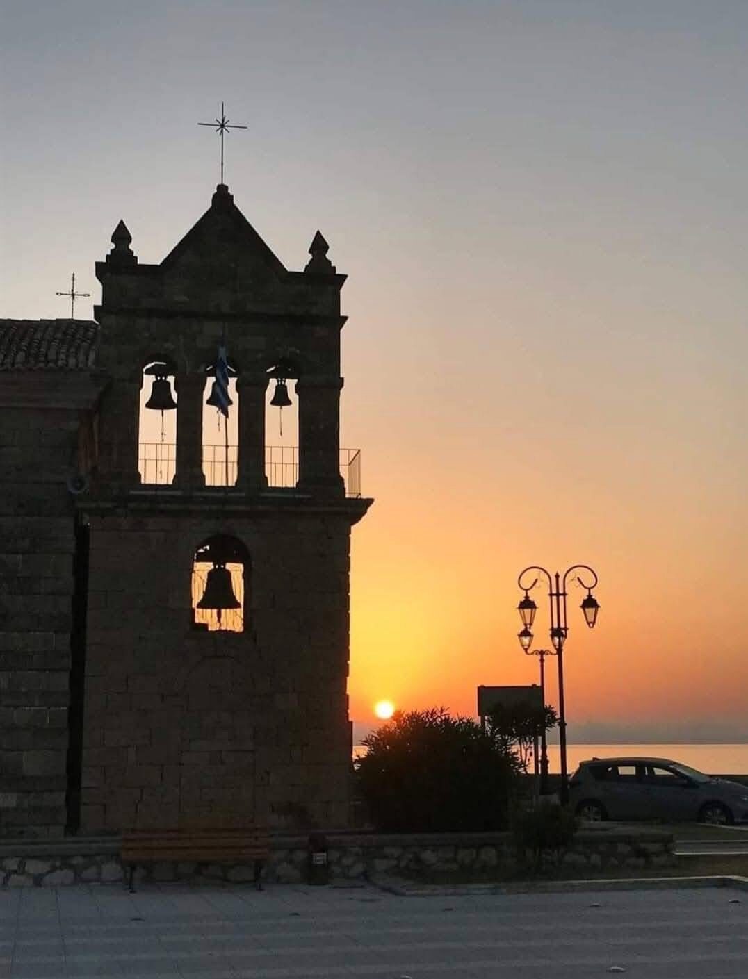 Church bell tower silhouette against a golden sunset sky